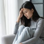 額に手を当てて考え込む女性