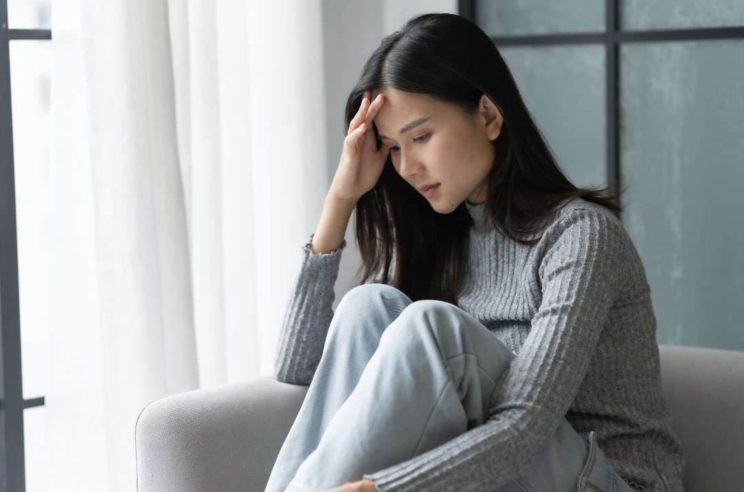 額に手を当てて考え込む女性