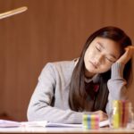 疲れている様子で頬杖をついている女性