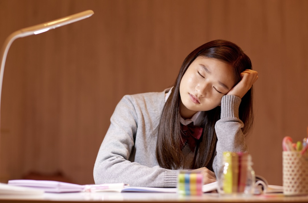 疲れている様子で頬杖をついている女性