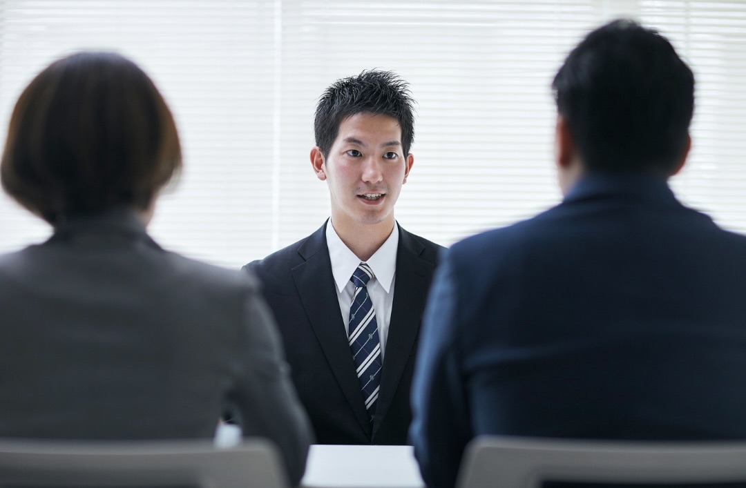 面接で2人の面接官と話している男性
