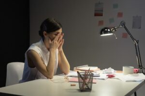 顔を手で覆って疲れている様子の女性