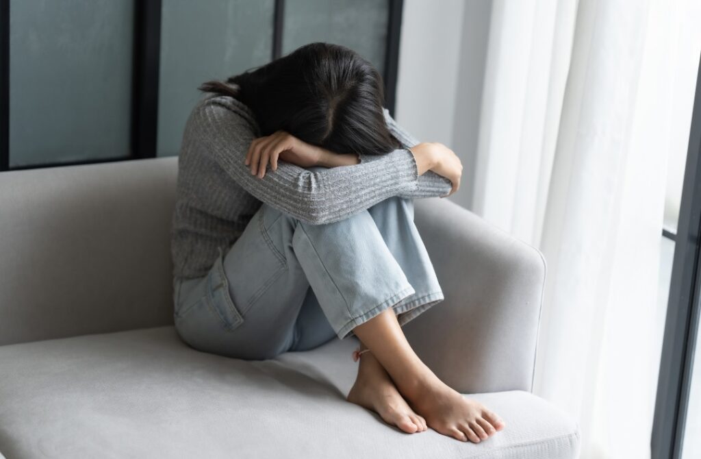 体育座りをして頭を突っ伏している女性