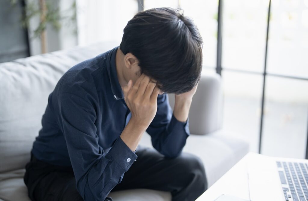 頭に手を当てて考え込む男性