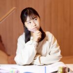 ノートを開きながら考えている様子の女性