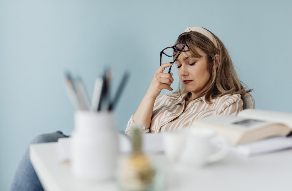 眼鏡を額に当てて悩む様子の女性