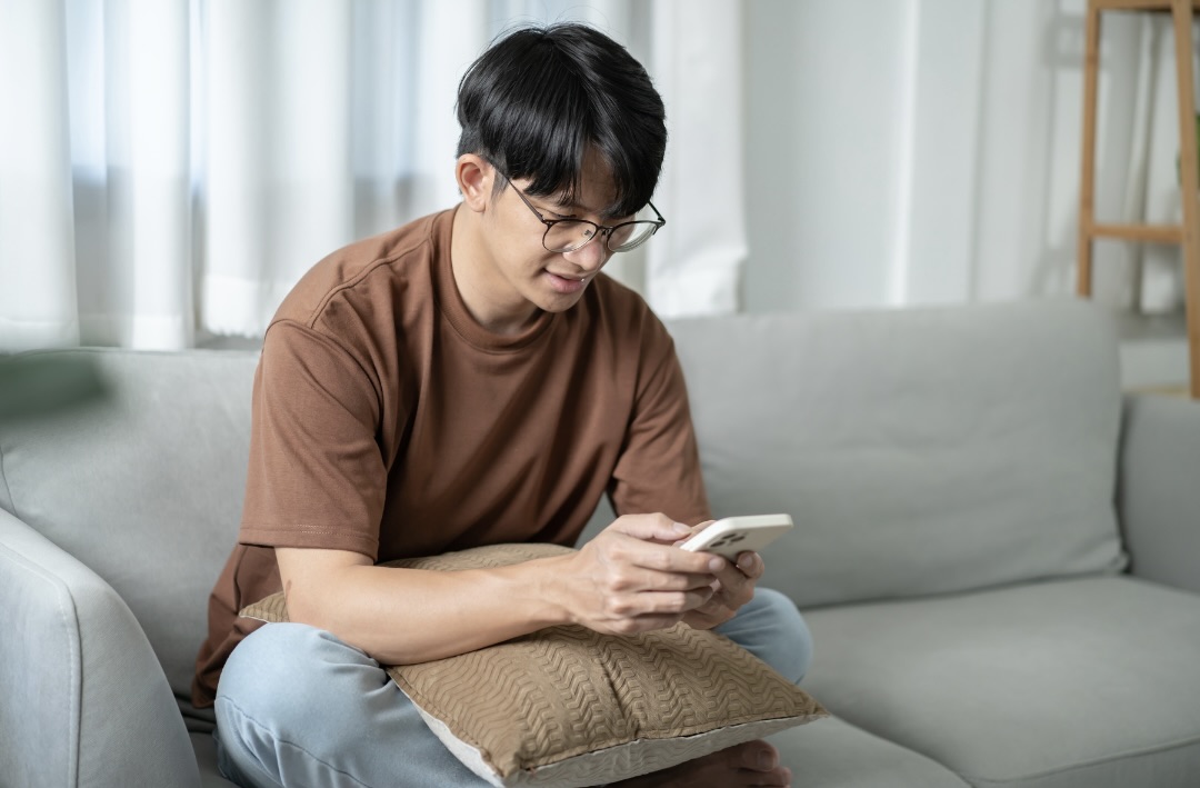 ソファーに座って携帯を触っている男性