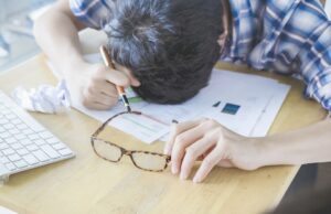 勉強中に机に突っ伏して落ち込む男性