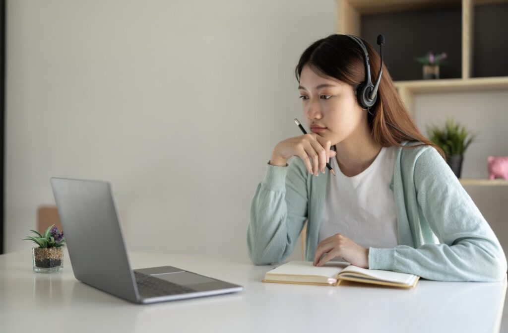 ヘッドホンをつけてパソコンを見ながら調べ物をしている女性