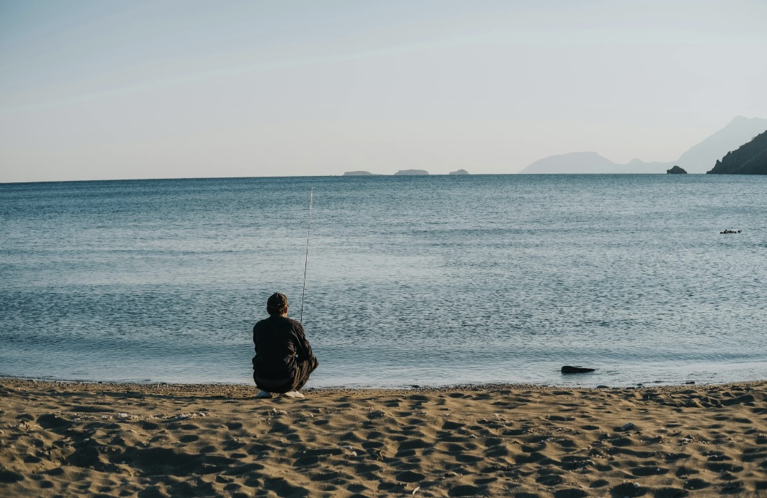海辺で1人で釣りをする人の後ろ姿