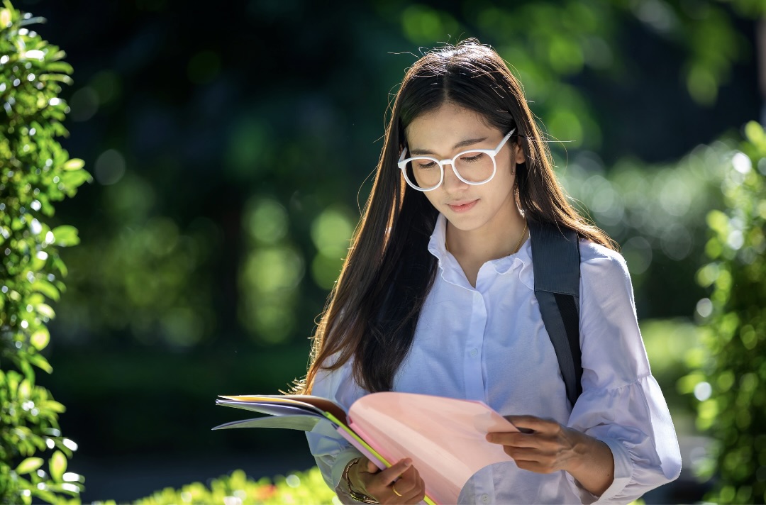 書類を読みながらキャンパスを歩く女性