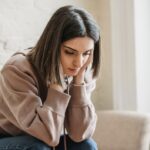 両耳に手を当てて深刻な顔で考えている女性